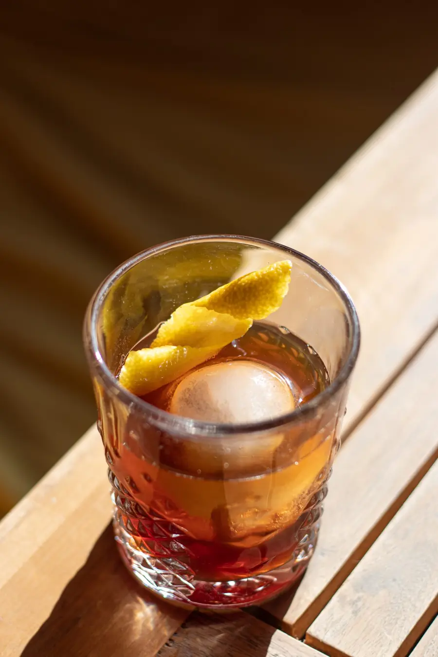 Amber cocktail in a patterned glass on a sunlit table